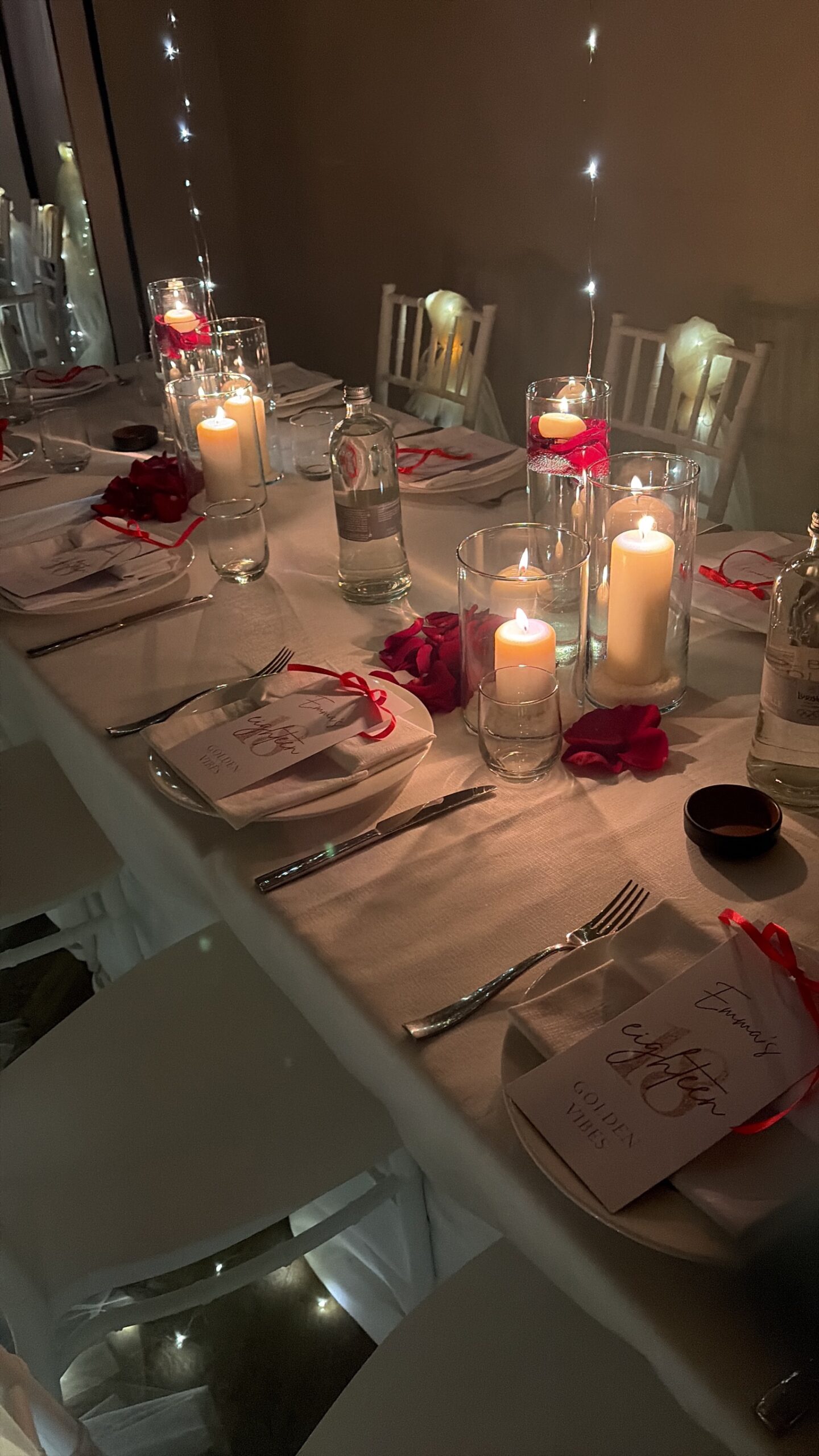 Tavola serale con candele, rose rosse e segnaposto calligrafati