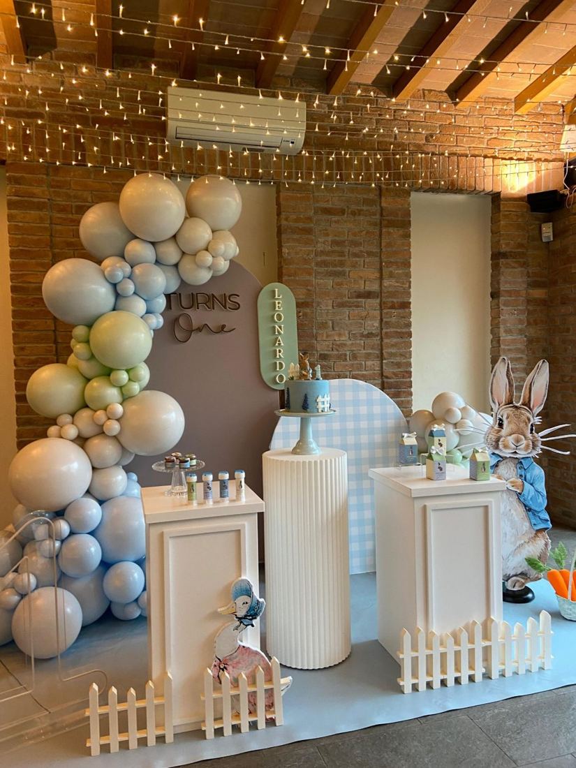 Allestimento con arco di palloncini pastello, pedane bianche e decorazioni a tema