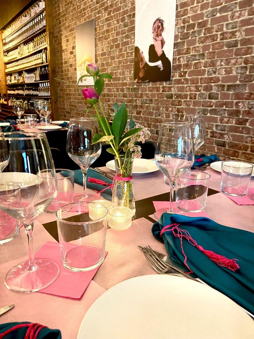 Tavola con tovaglioli rosa e verde in sala con mattoni a vista